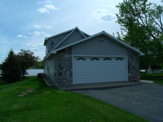 15117 Valley Dr, Wolverine, MI 49799 - view of side of home with stone siding, asphalt driveway, a yard, central air condition unit, and an attached garage