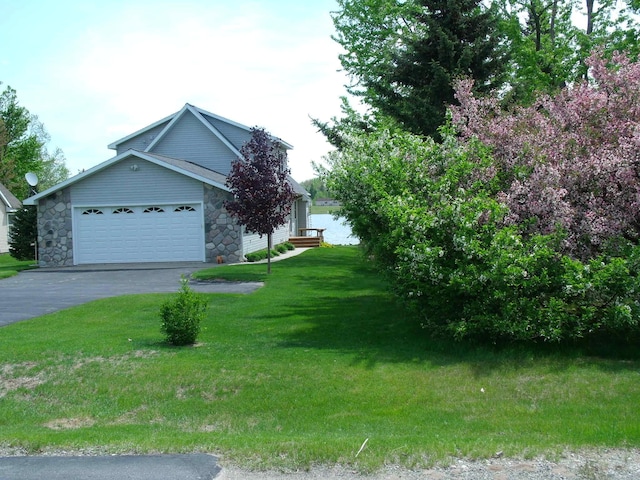 15117 Valley Dr, Wolverine, MI 49799 - view of side of home featuring driveway, a yard, stone siding, and a garage