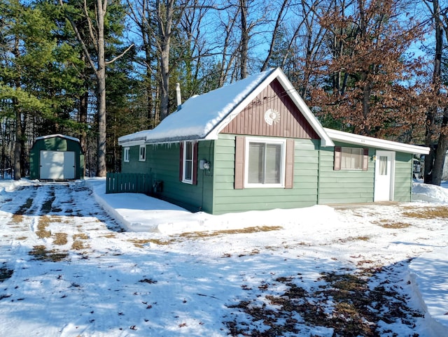 snow covered structure with an outbuilding and a shed