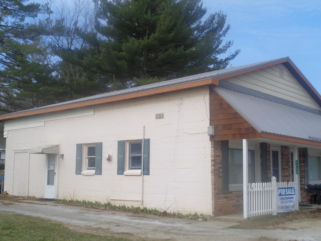 5407 W Houghton Lake Dr, Houghton Lake, MI 48629 - view of side of property with covered porch, concrete block siding, and metal roof