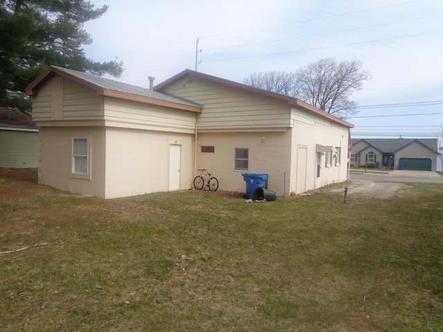 5407 W Houghton Lake Dr, Houghton Lake, MI 48629 - back of house featuring a lawn, concrete block siding, and metal roof