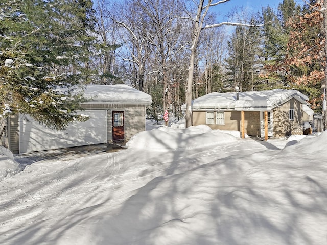 snowy yard featuring an outbuilding and a detached garage