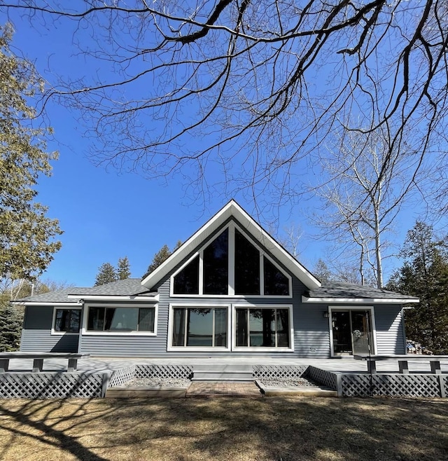 rear view of property featuring a wooden deck and roof with shingles