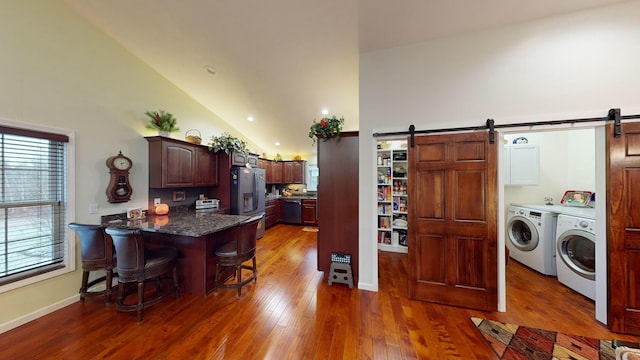 kitchen with a kitchen bar, a barn door, appliances with stainless steel finishes, a peninsula, and separate washer and dryer