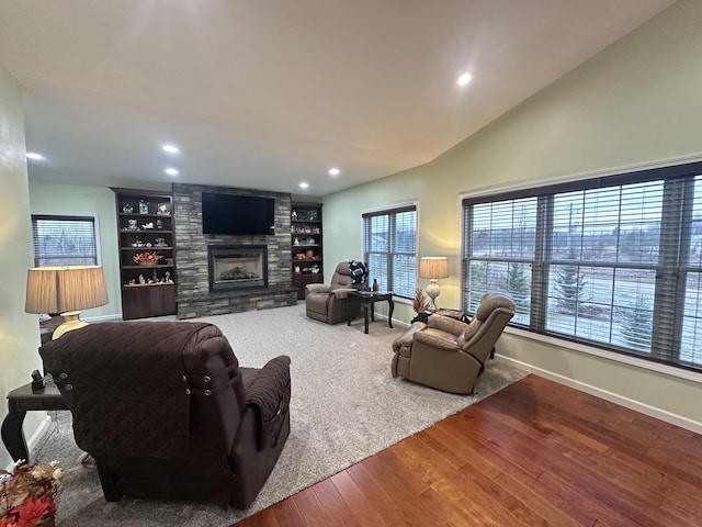 living room with wood finished floors, recessed lighting, a stone fireplace, baseboards, and vaulted ceiling