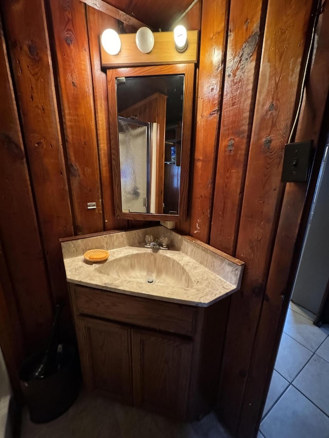 bathroom with wooden walls, vanity, and tile patterned flooring