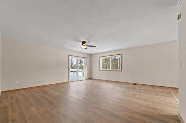 empty room featuring baseboards, ceiling fan, a textured ceiling, and light wood-style floors