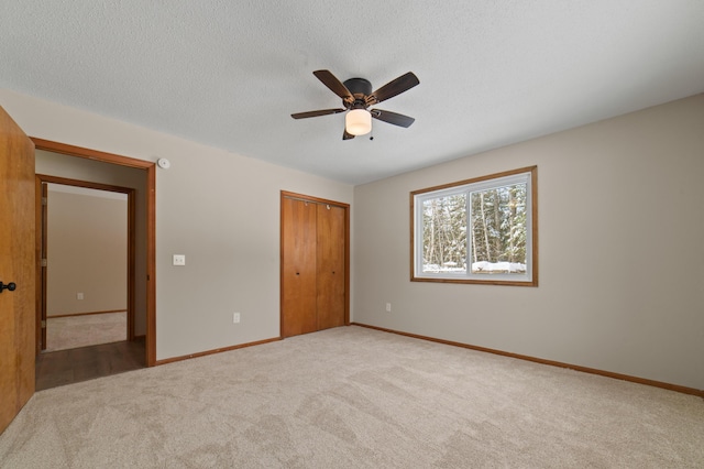 unfurnished bedroom with a ceiling fan, baseboards, a closet, a textured ceiling, and carpet flooring