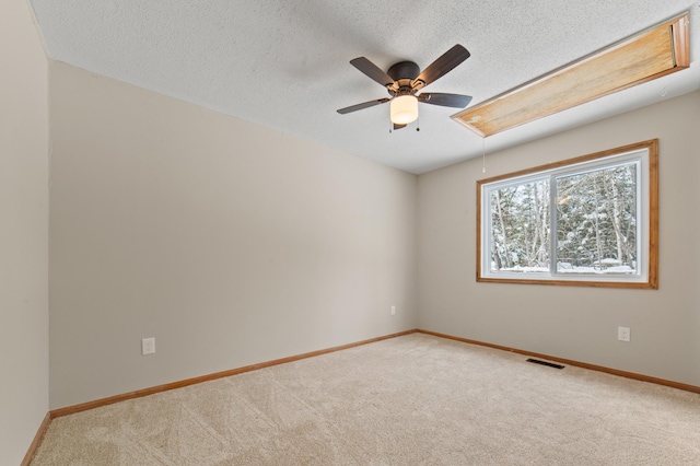 carpeted spare room featuring visible vents, a textured ceiling, attic access, and baseboards