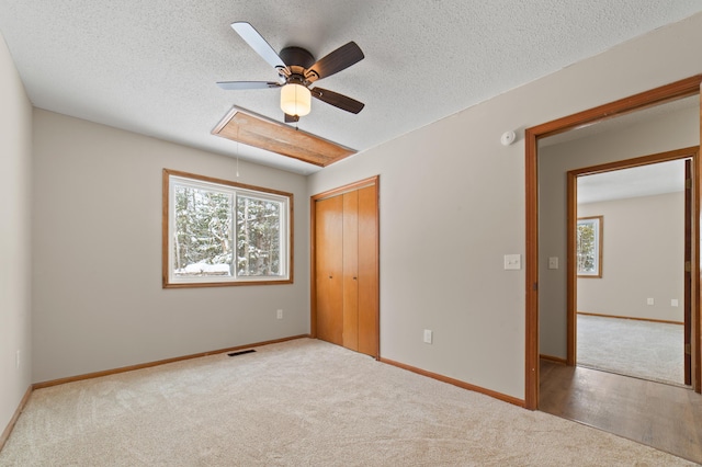 unfurnished bedroom with visible vents, carpet floors, baseboards, attic access, and a closet