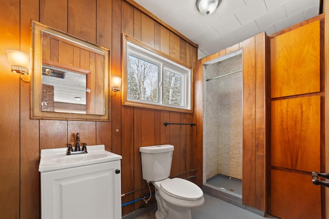 full bath featuring wooden walls, a stall shower, toilet, and vanity