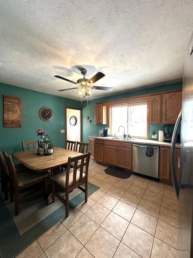 kitchen with a sink, appliances with stainless steel finishes, light tile patterned floors, and light countertops