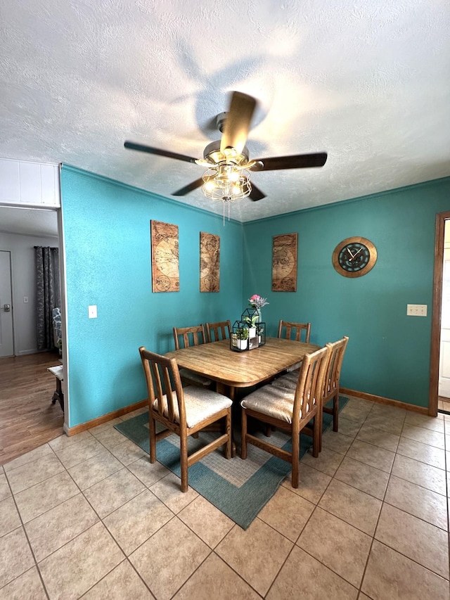 dining room featuring light tile patterned flooring, baseboards, a textured ceiling, and a ceiling fan