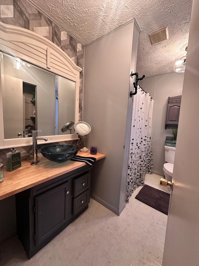 full bath with visible vents, curtained shower, toilet, vanity, and a textured ceiling