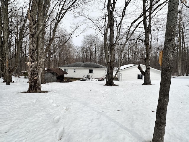 yard layered in snow with a garage and an outbuilding