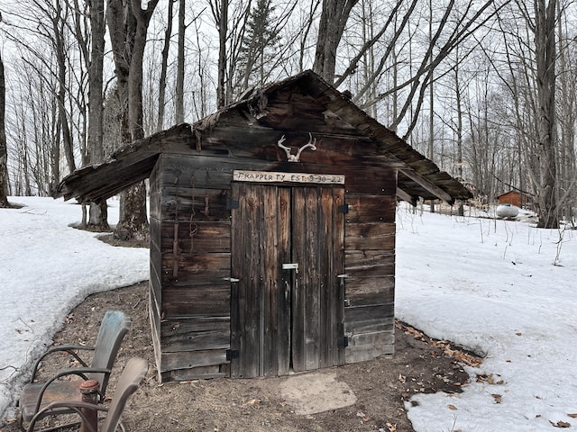 snow covered structure with a storage unit and an outbuilding