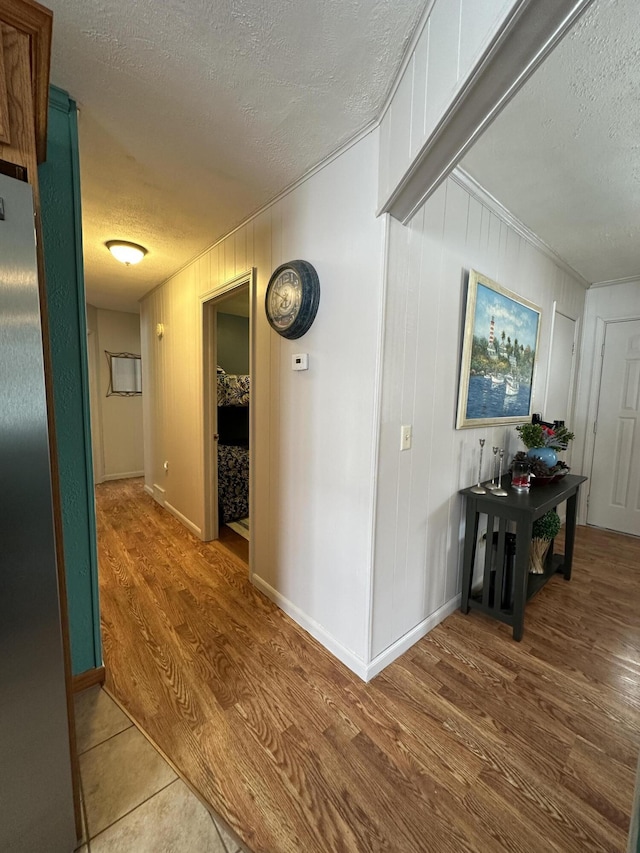 hall with wood finished floors, baseboards, and a textured ceiling