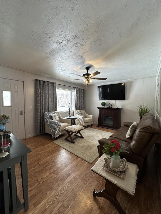 living room with a fireplace, a textured ceiling, wood finished floors, and ceiling fan