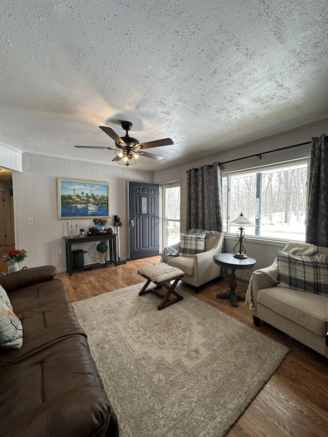 living room featuring a textured ceiling, wood finished floors, and ceiling fan