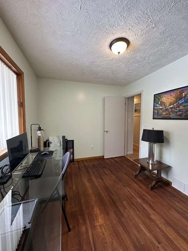 office space with visible vents, baseboards, a textured ceiling, and wood finished floors