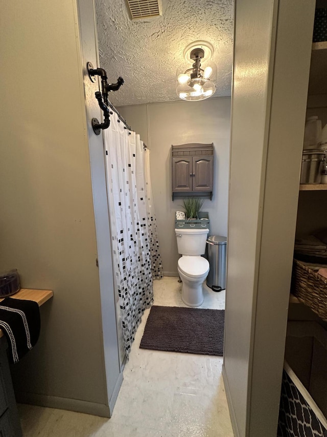 bathroom featuring a shower with curtain, baseboards, visible vents, a textured ceiling, and toilet