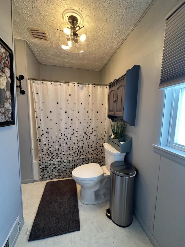 bathroom with curtained shower, toilet, visible vents, and a textured ceiling