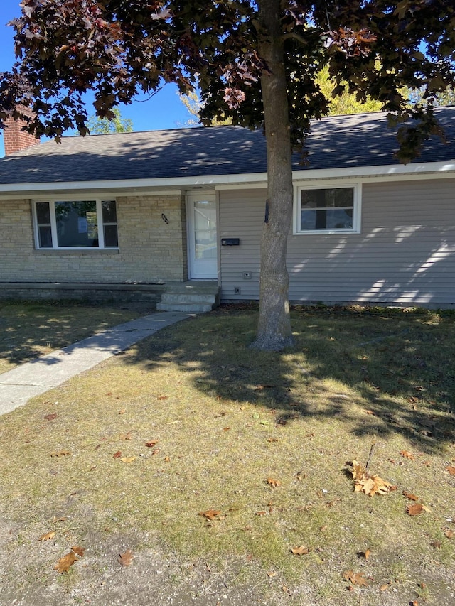 single story home featuring a front lawn, brick siding, and roof with shingles