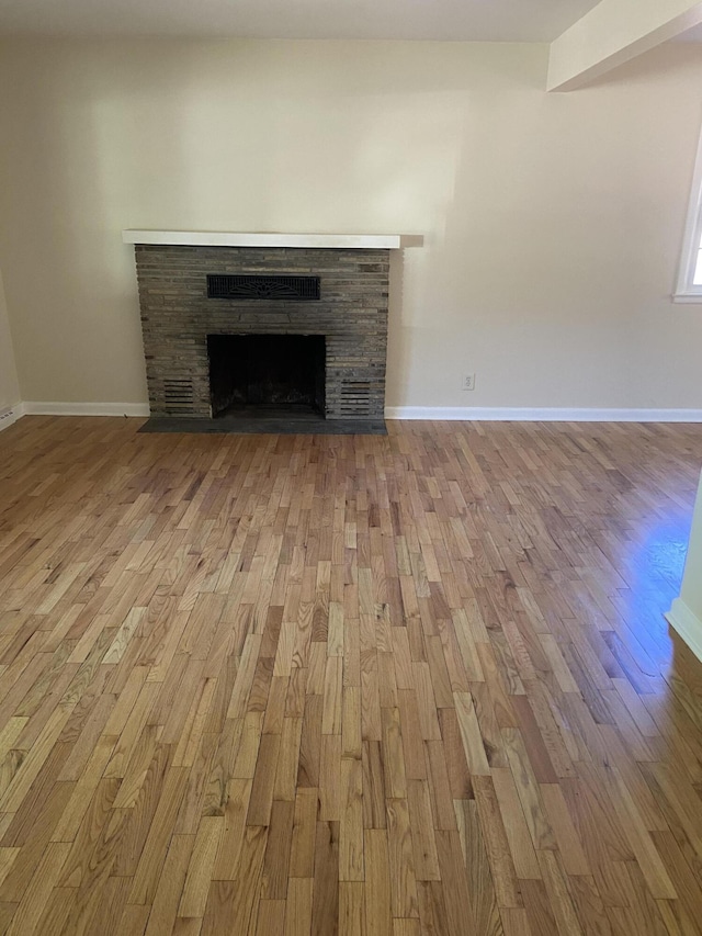 details featuring a stone fireplace, baseboards, and wood finished floors