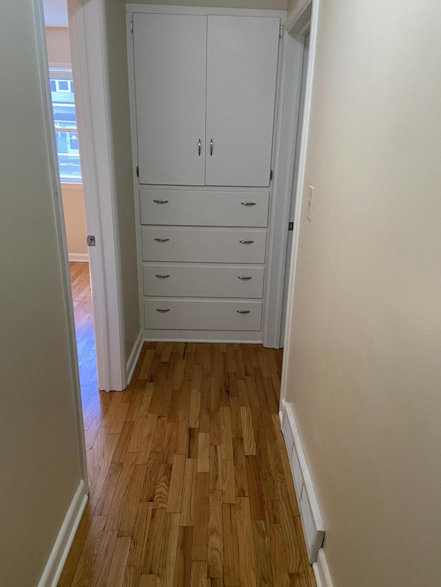 corridor with baseboards and light wood-style floors