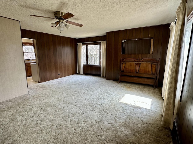 916 W First St, Cheboygan, MI 49721 - spare room featuring a textured ceiling, wooden walls, a ceiling fan, and light carpet