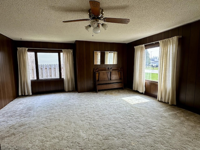916 W First St, Cheboygan, MI 49721 - unfurnished room with wood walls, a ceiling fan, a textured ceiling, and light colored carpet