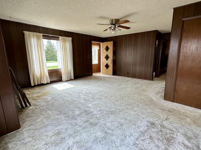 916 W First St, Cheboygan, MI 49721 - carpeted empty room with wooden walls, a textured ceiling, and ceiling fan