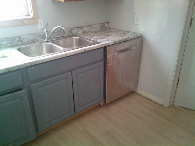 kitchen featuring light wood-style flooring, light countertops, and a sink