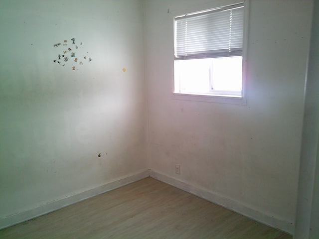 spare room with baseboards and light wood finished floors