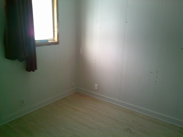 empty room featuring light wood-type flooring and baseboards