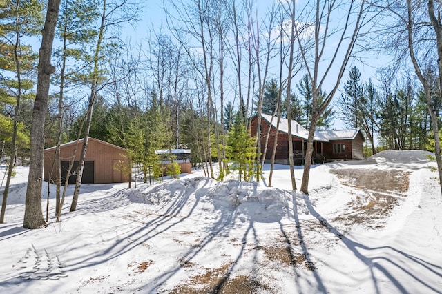 yard covered in snow featuring a pole building, an outbuilding, and a detached garage