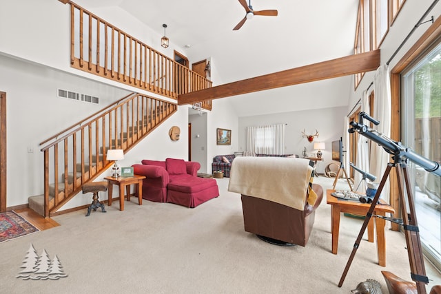 carpeted living area featuring visible vents, stairs, a high ceiling, and ceiling fan