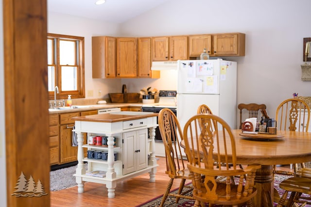 kitchen with white appliances, ventilation hood, lofted ceiling, light countertops, and light wood-style floors