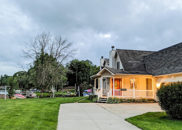 view of home's exterior featuring a yard, covered porch, a shingled roof, a chimney, and concrete driveway