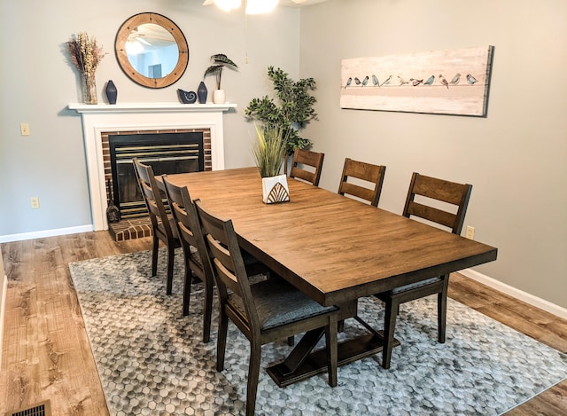 dining space featuring wood finished floors, a fireplace, and baseboards