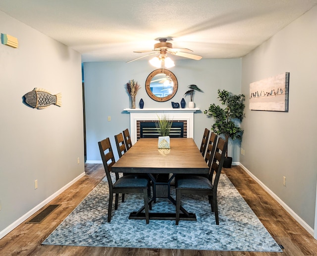 dining room featuring wood finished floors, visible vents, baseboards, ceiling fan, and a textured ceiling