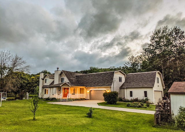 view of front facade with a gambrel roof, concrete driveway, a front yard, roof with shingles, and an attached garage