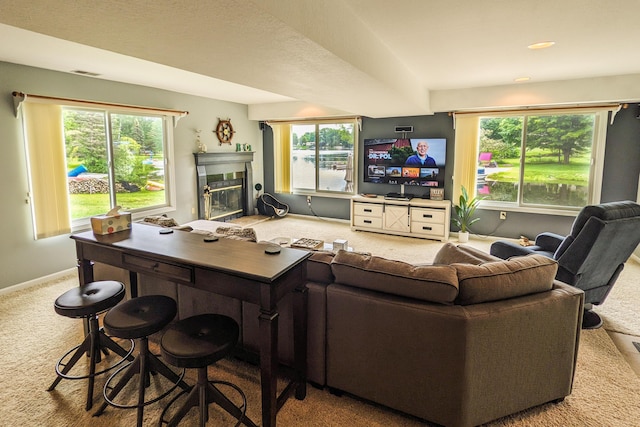 living room with visible vents, carpet floors, a healthy amount of sunlight, and a glass covered fireplace