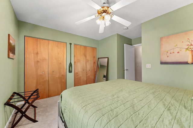 carpeted bedroom with two closets and a ceiling fan