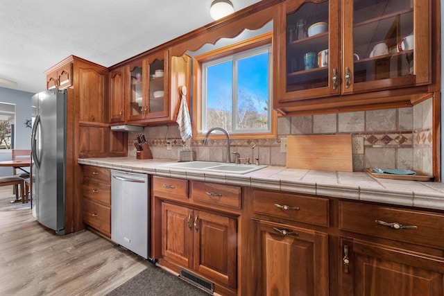 kitchen featuring visible vents, decorative backsplash, brown cabinets, appliances with stainless steel finishes, and a sink