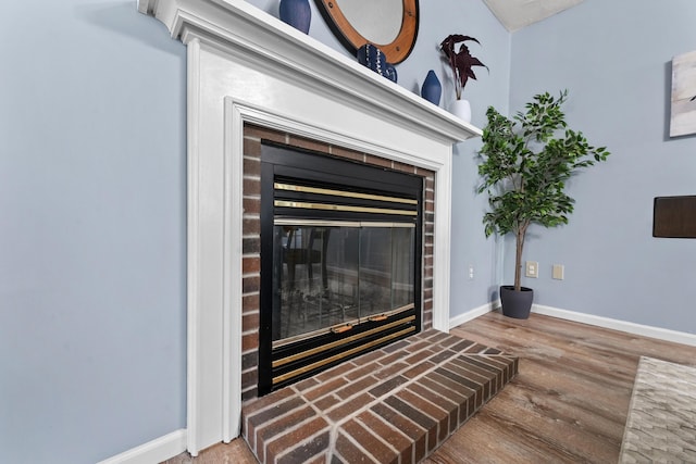 details with a brick fireplace, baseboards, and wood finished floors