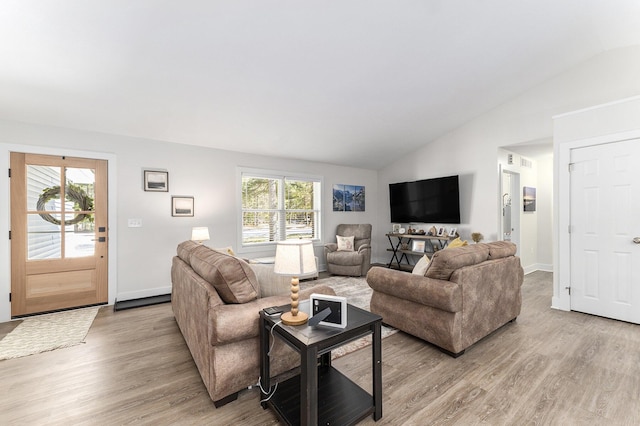 living room featuring light wood finished floors, a healthy amount of sunlight, and lofted ceiling