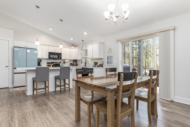 dining space with a chandelier, recessed lighting, lofted ceiling, and light wood-style floors
