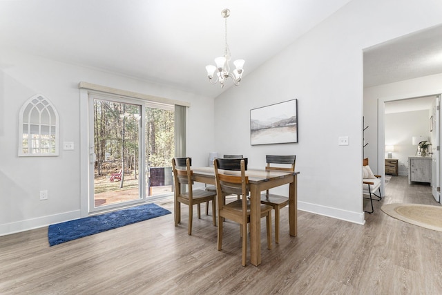 dining room with an inviting chandelier, baseboards, lofted ceiling, and wood finished floors