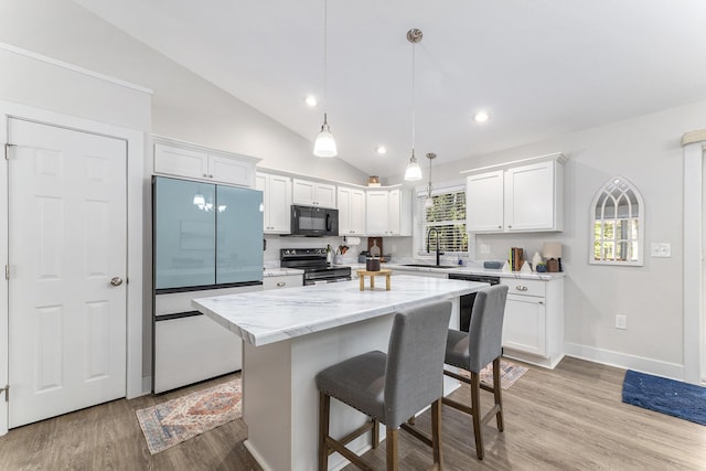 kitchen featuring stainless steel electric stove, white cabinets, a kitchen bar, and black microwave